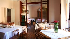 A dining area with multiple tables and chairs, a wooden partition, and hanging light fixtures. - Hotel Al Sogno (Alassio)