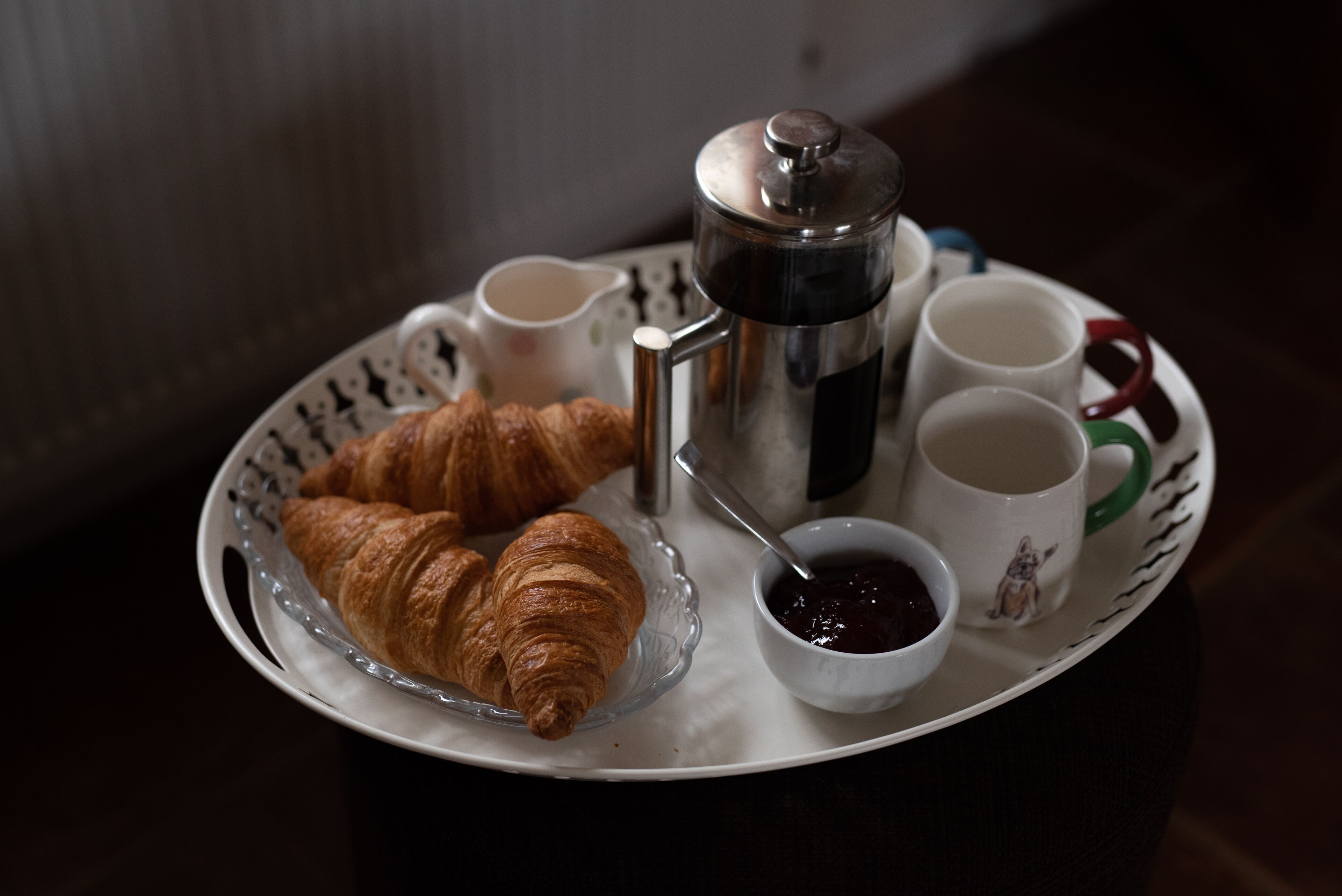 Aamiaistarjotin, jossa on croissantteja, kahvipannu ja kuppeja.