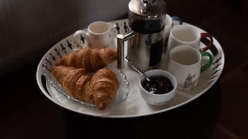 Aamiaistarjotin, jossa on croissantteja, kahvipannu ja kuppeja.