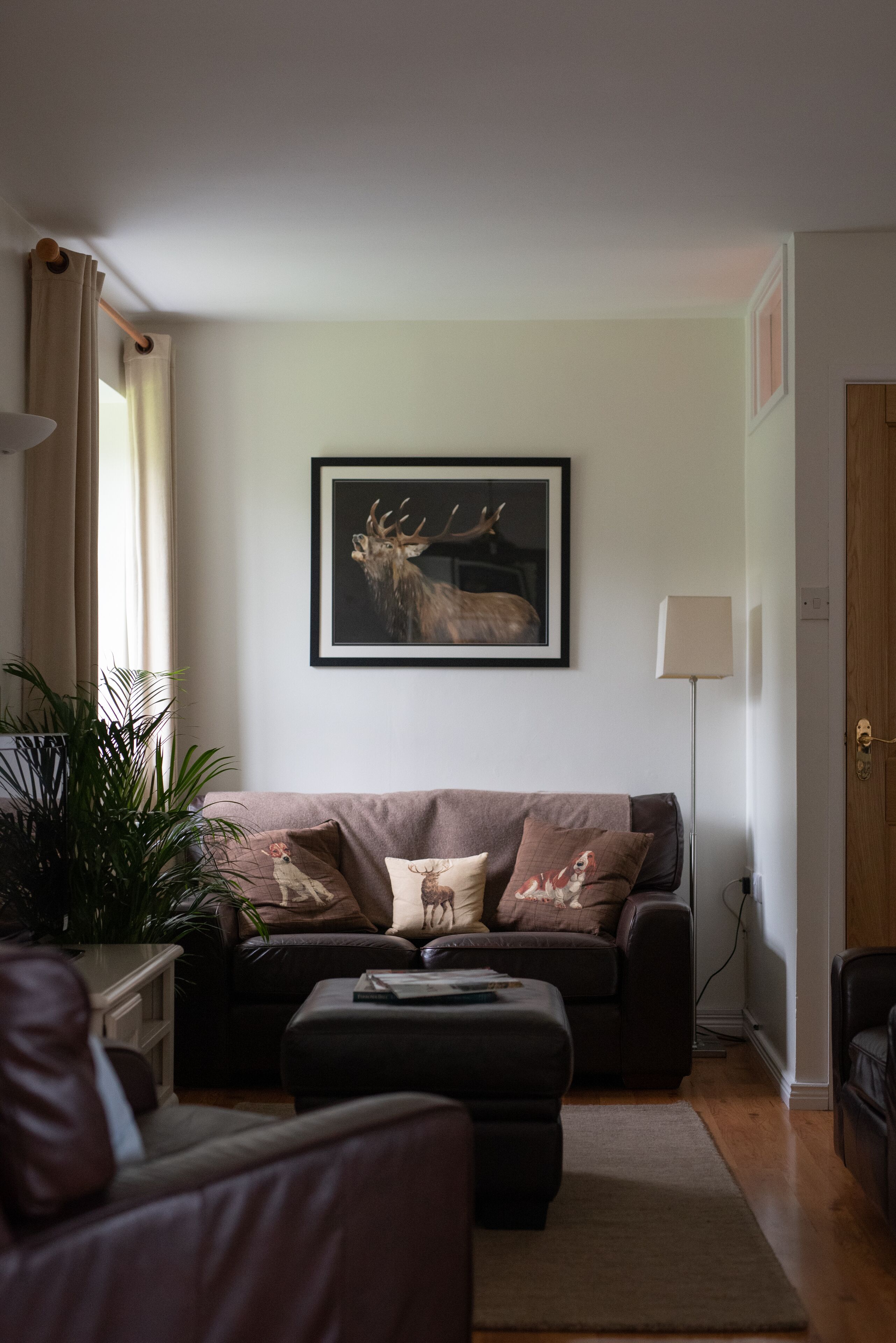 A living room with a brown sofa, a coffee table, and a framed deer picture on the wall.