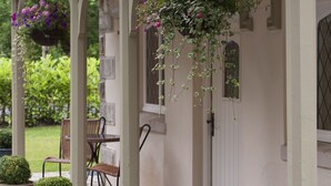 A covered porch with a white door, potted plants, and hanging flower baskets.