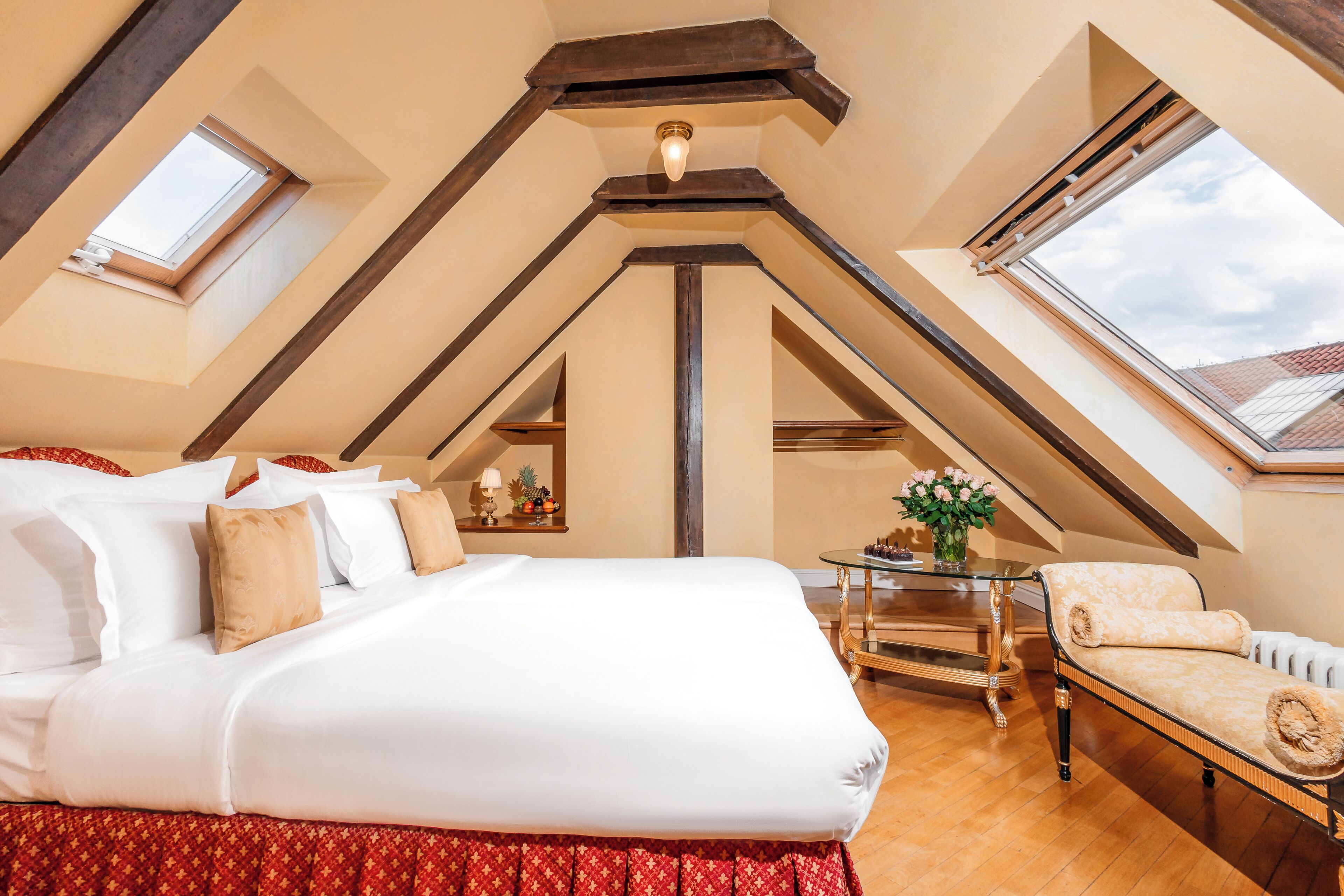 Un dormitorio con una cama grande, un sofá, una mesita y una ventana.