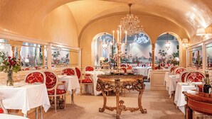 A luxurious dining room with ornate chandeliers, red upholstered chairs, and white tablecloths. - Alchymist Grand Hotel & Spa (Prague)