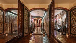 Un vaste hall d’entrée agrémenté de décorations somptueuses, un mur en pierre et un escalier menant à un niveau supérieur.