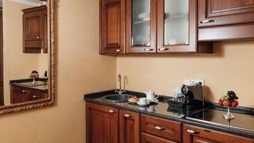 A kitchen with wooden cabinets, a large mirror, a countertop with a coffee maker, and a fruit bowl.