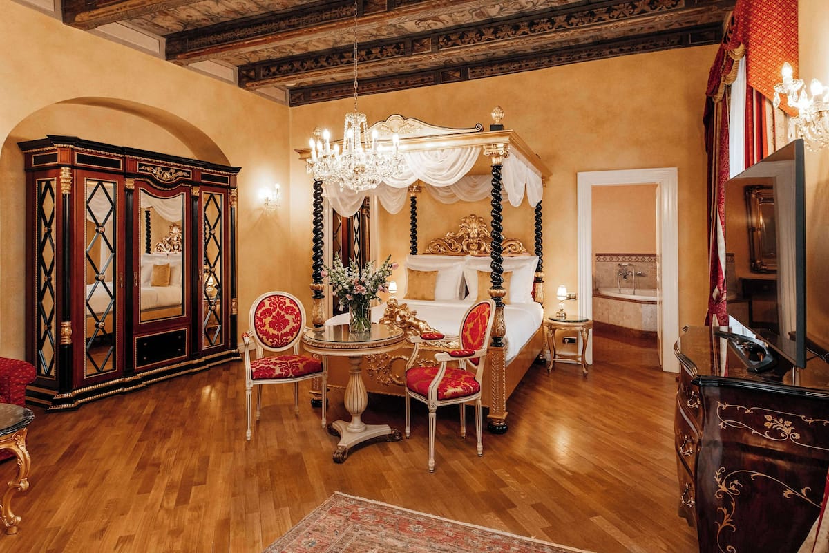 Ein luxuriöses Schlafzimmer mit Himmelbett, aufwendigen Möbeln und einer Chandelüster.