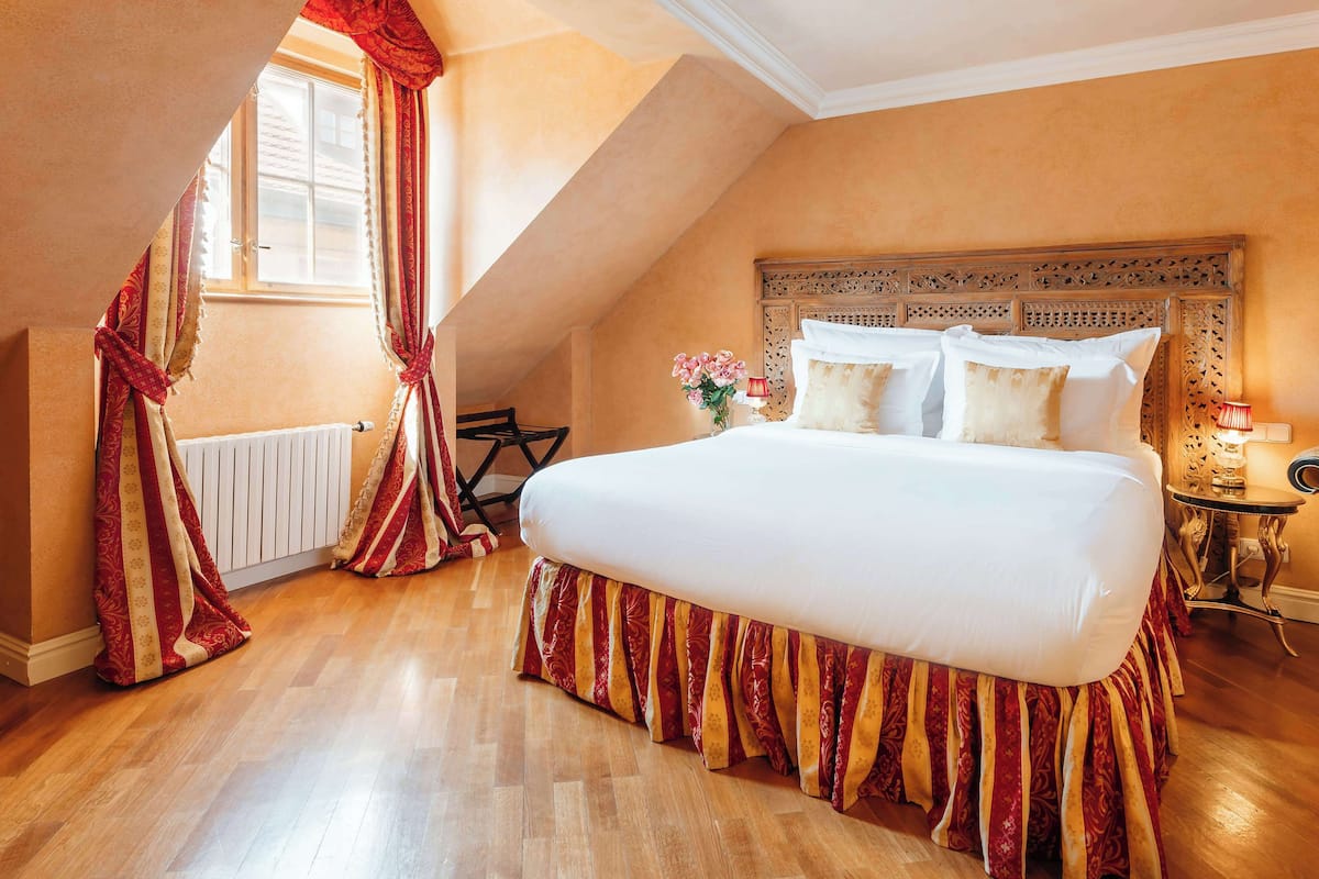 Ein Schlafzimmer mit einem großen Bett, einem Holzkopfteil, einem Heizkörper und einem Fenster mit Vorhängen.
