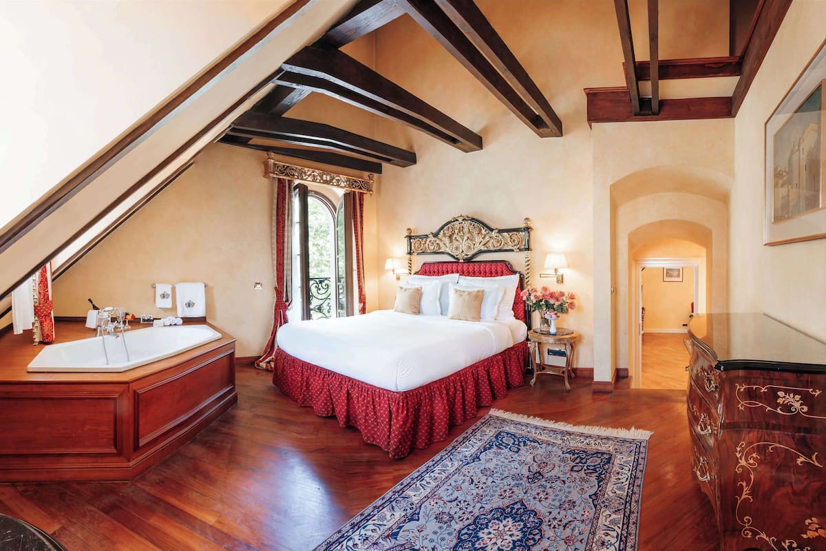 Ein Schlafzimmer mit einem großen Bett, einem Holz-Waschtisch, einer Badewanne und einem roten Bettlaken.