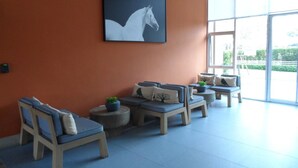 A modern lounge area with a large window, a white horse painting on the wall, and several seating options. - Bann Thew Lom By Paninthira (Cha-am)