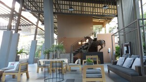 A spacious lobby with a staircase, seating areas, and a large sculpture. - Bann Thew Lom By Paninthira (Cha-am)