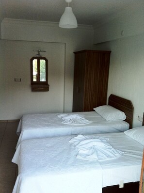 Une chambre d’hôtel avec deux lits, une armoire en bois et un luminaire suspendu.