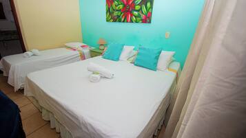 Habitación de hotel con dos camas individuales, cada una con ropa blanca y una almohada. Hay un cuadro de flores en la pared sobre las camas.