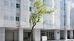 A modern building with a tree in front, columns, and a number '61' on a pillar. - The Carlton (Taichung)