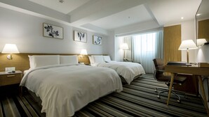 A hotel room with two beds, a desk, and a chair. There are wall-mounted lamps, a window with curtains, and framed artwork on the wall. - The Carlton (Taichung)