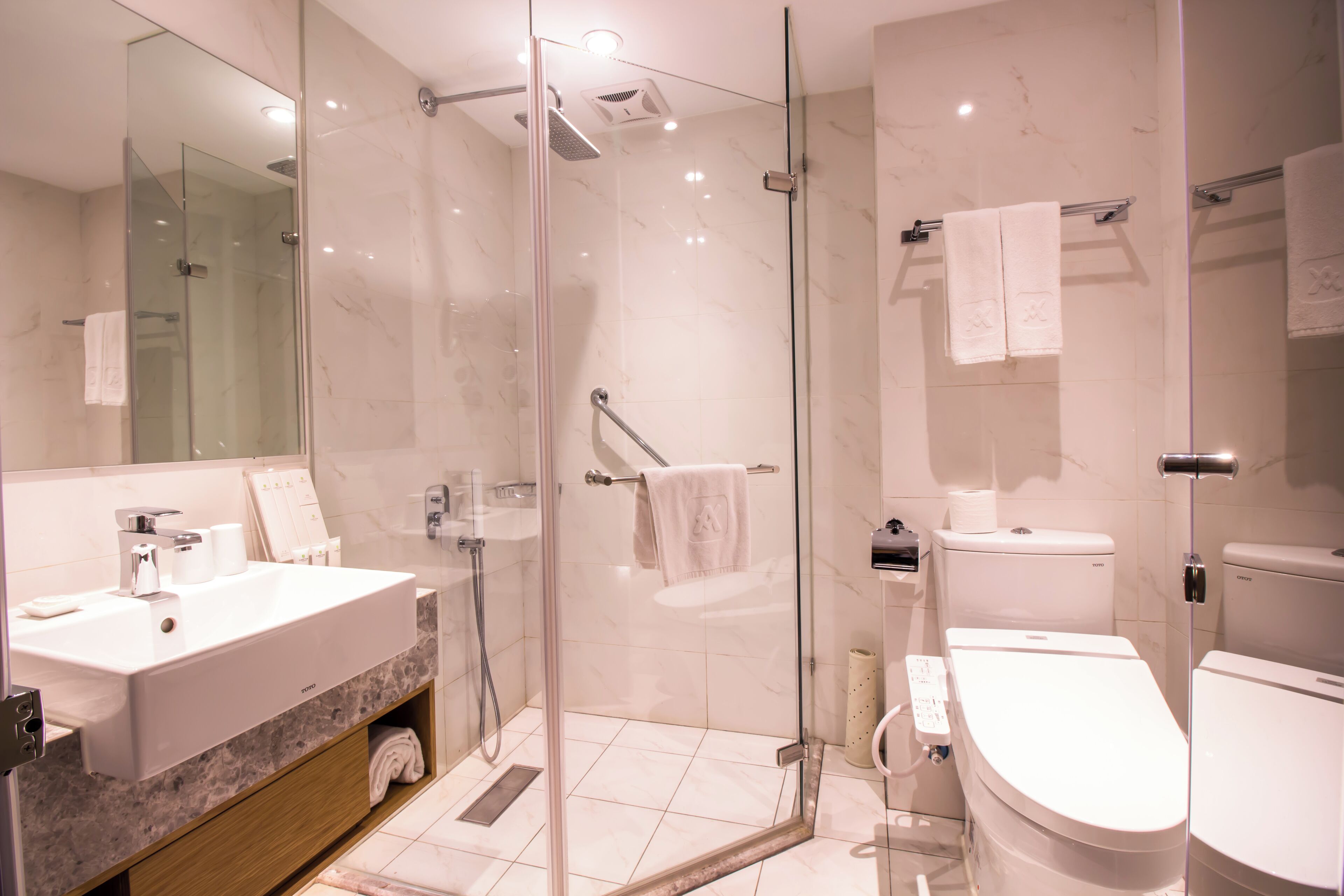 Un baño moderno con ducha de vidrio, lavamanos blanco y retrete.