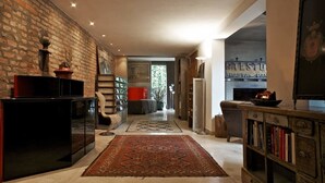 A modern living room with a brick wall, a black entertainment unit, a red sofa, a patterned rug, and a bookshelf. - B&B Design (Bologna)