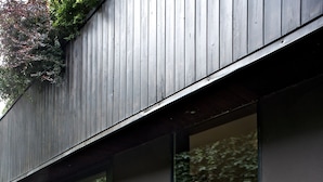 A modern building with large glass windows and a dark exterior. - B&B Design (Bologna)
