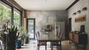 A spacious dining area with a long table, chairs, potted plants, and a refrigerator. - B&B Design (Bologna)