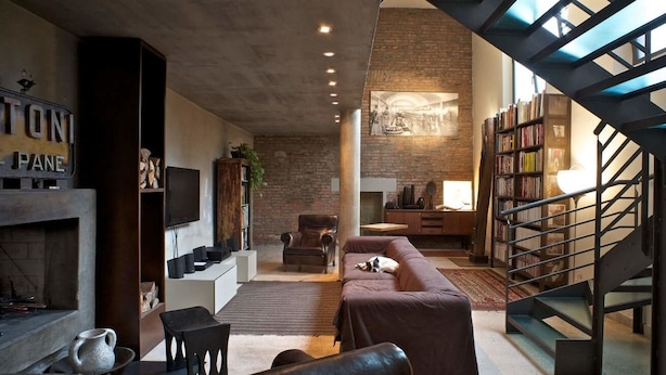 A modern living room with a fireplace, a staircase, and a bookshelf. - B&B Design (Bologna)
