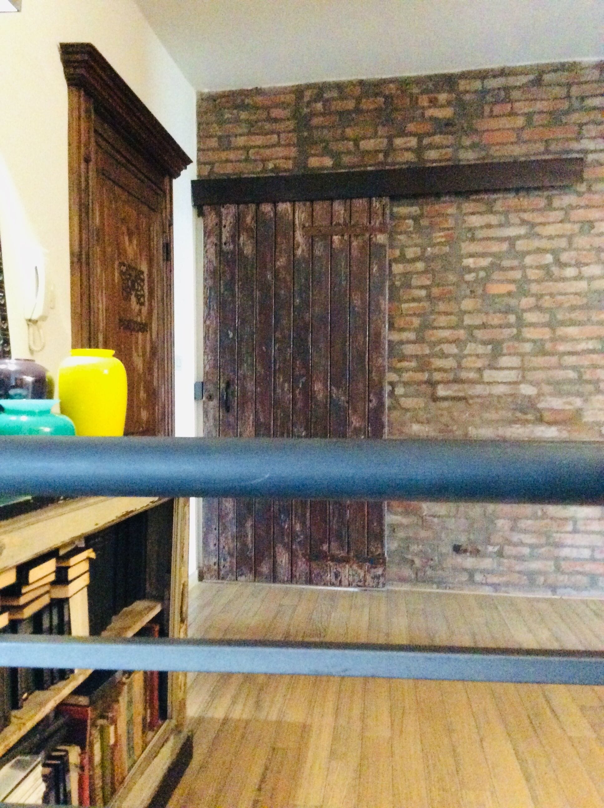 A room with a wooden floor, a brick wall, and a wooden door.