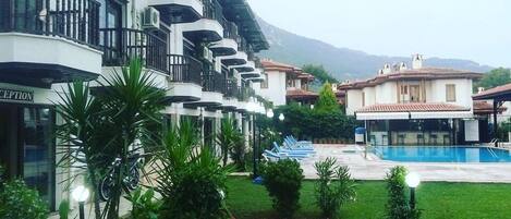 A hotel with multiple balconies, a swimming pool, and a reception area.