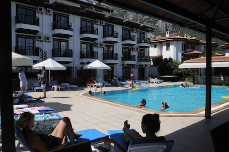 Una piscina al aire libre, sombrillas, sillones reclinables de piscina