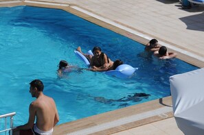 Una piscina al aire libre, sombrillas, sillones reclinables de piscina