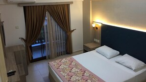 A hotel room with a bed, a nightstand, a lamp, an air conditioner, and a view of the outside through a window with curtains. - Hamle Hotel (Ula)
