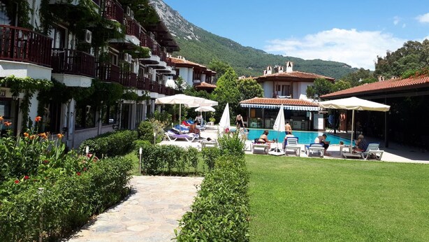 A hotel courtyard with a swimming pool, outdoor seating, and a mountain backdrop. - Hamle Hotel (Ula)
