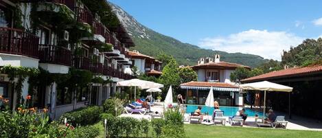 Una piscina al aire libre, sombrillas, sillones reclinables de piscina