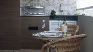 A kitchen with patterned tiles, a black hood, and a dining area with wicker chairs and a table set for two. - Doce Lar de Bertioga (Bertioga)