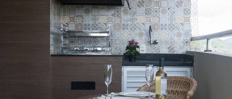 A kitchen with patterned tiles, a black hood, and a dining area with wicker chairs and a table set for two.