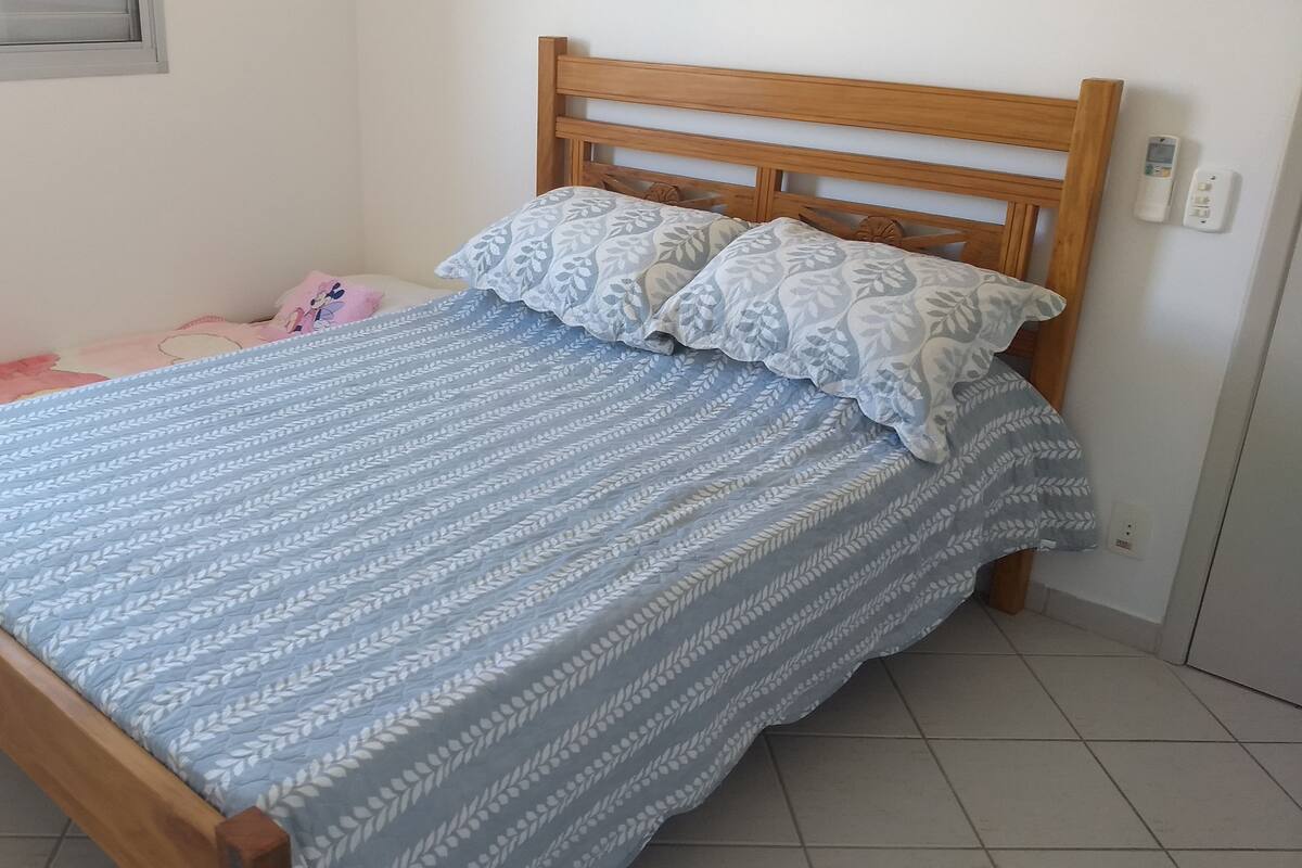 Un lit avec une tête de lit en bois, une couvre-lit à motifs et des oreillers.