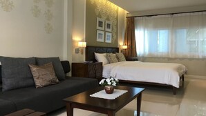 A hotel room with a bed, a sofa, a nightstand, and a coffee table. - Bann Vimansamutr (Cha-am)
