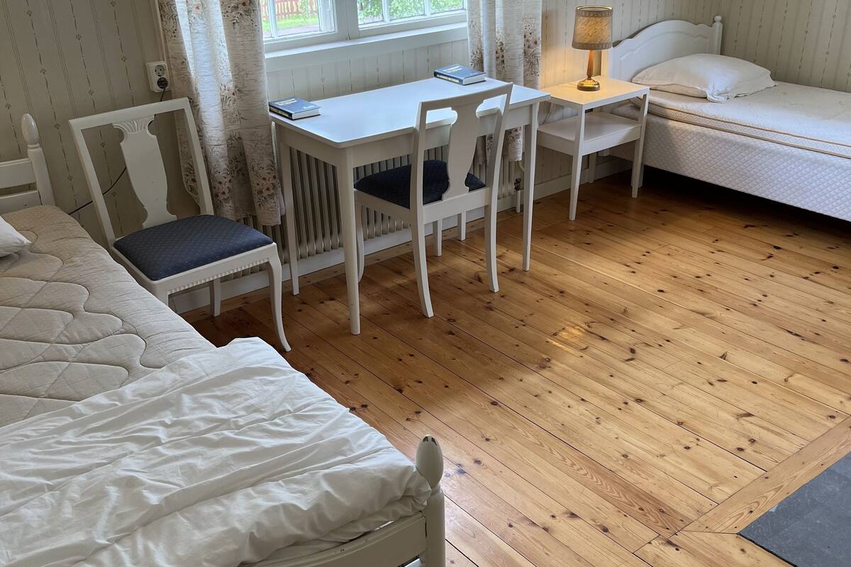 Un dormitorio con cama, escritorio, silla y ventana con cortinas.