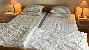 Una cama con estructura de madera, dos mesitas de noche y dos lámparas.