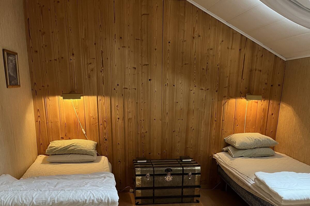 Una habitación con dos camas individuales, paredes de madera y suelo de madera.