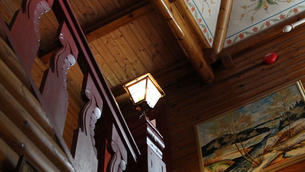 A wooden ceiling with a traditional light fixture and a framed landscape painting.