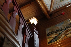 Un plafond en bois agrémenté d’un luminaire traditionnel et d’un tableau représentant un paysage, encadré.