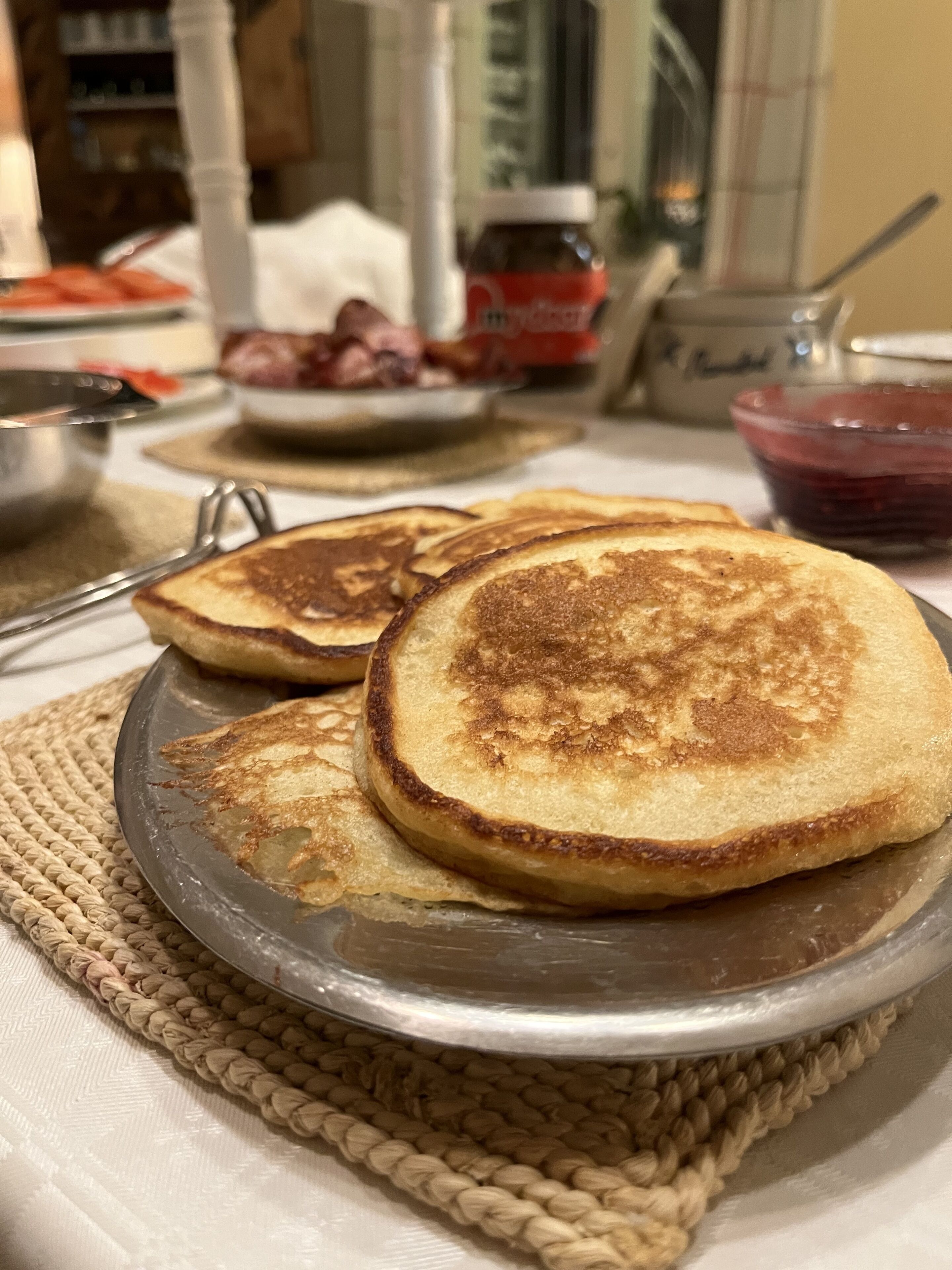 A plate of golden-brown pancakes on a woven placemat.