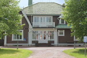 En tvåvåningsbyggnad i trä med en vit veranda och en entré som är anpassad för rullstolsburna.