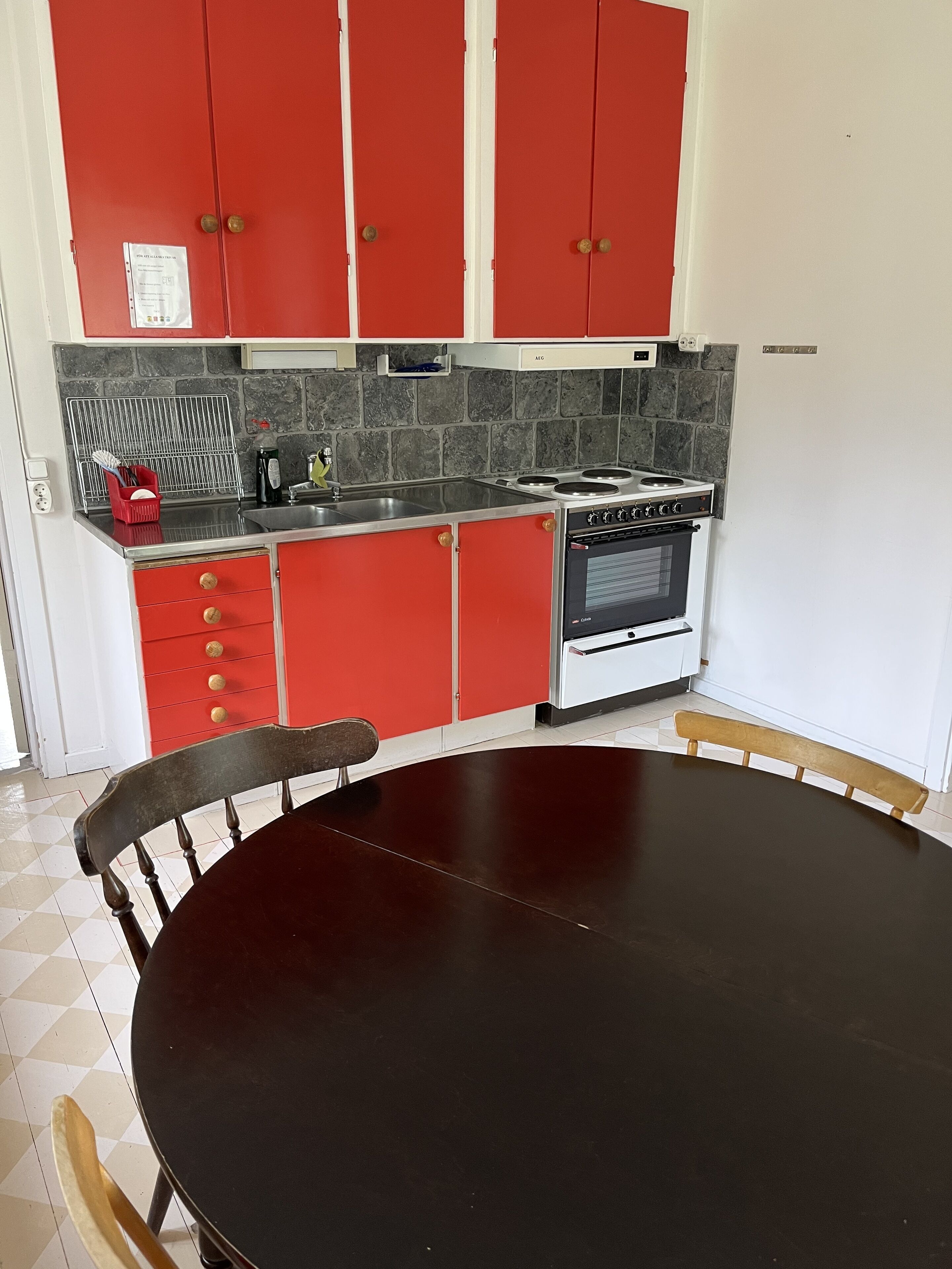 Een keuken met rode kastjes, een fornuis en een spoelbak.