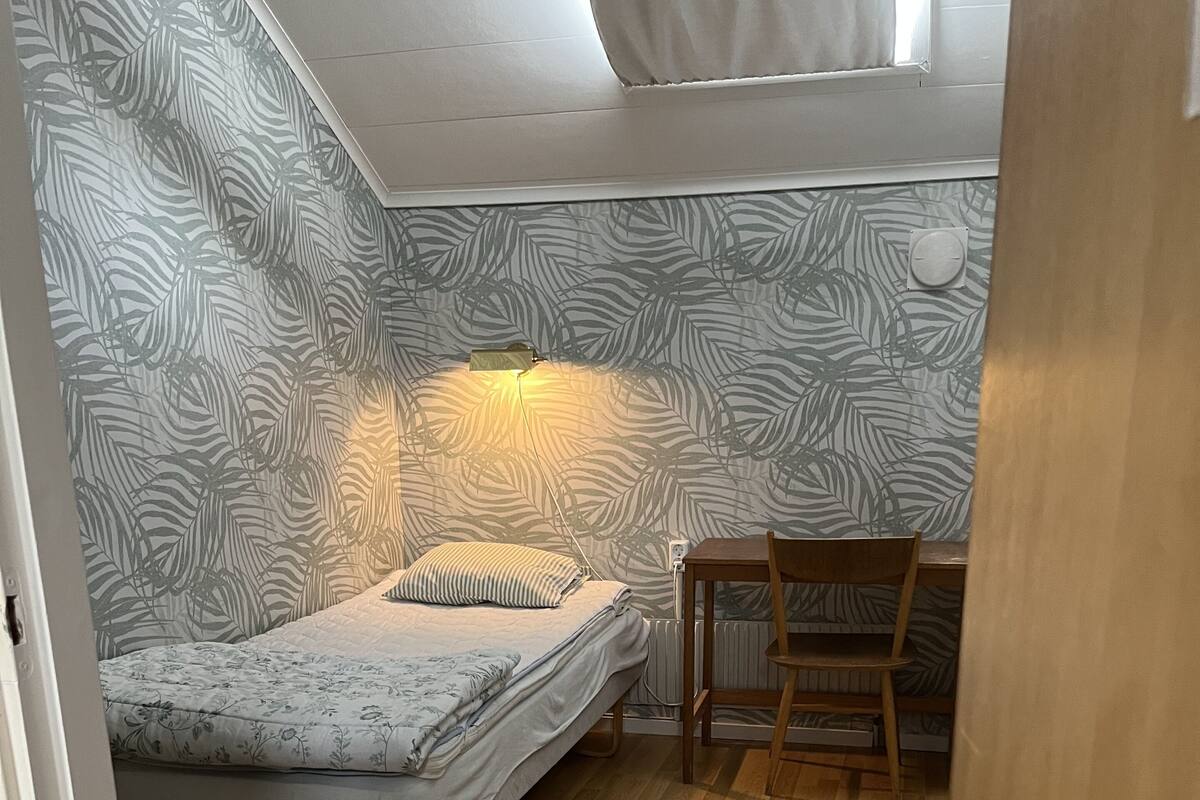 Una habitación pequeña y acogedora con una cama, una silla y un radiador.
