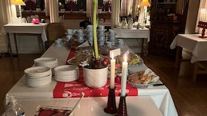 A dining area with tables set for a meal, featuring a variety of dishes and tableware.