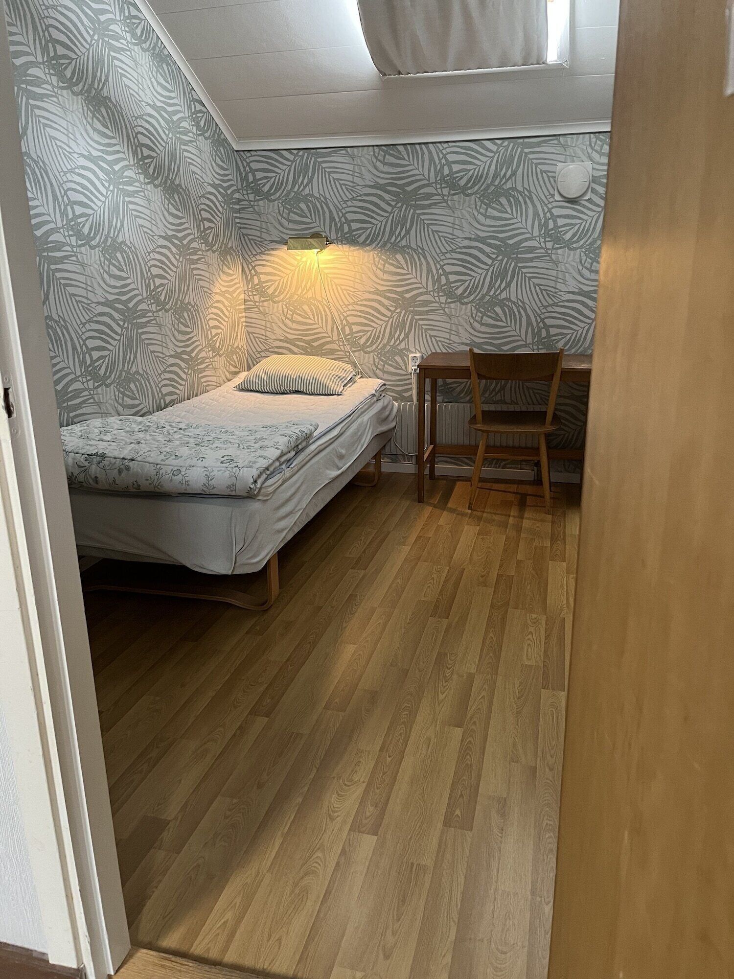 A small, compact room with a bed, a chair, and a desk.