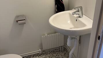 A bathroom with a white sink, toilet, and radiator.