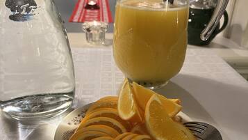 Una jarra de vidrio con jugo de naranja, un vaso de agua y un plato con rodajas de naranja sobre una mesa.