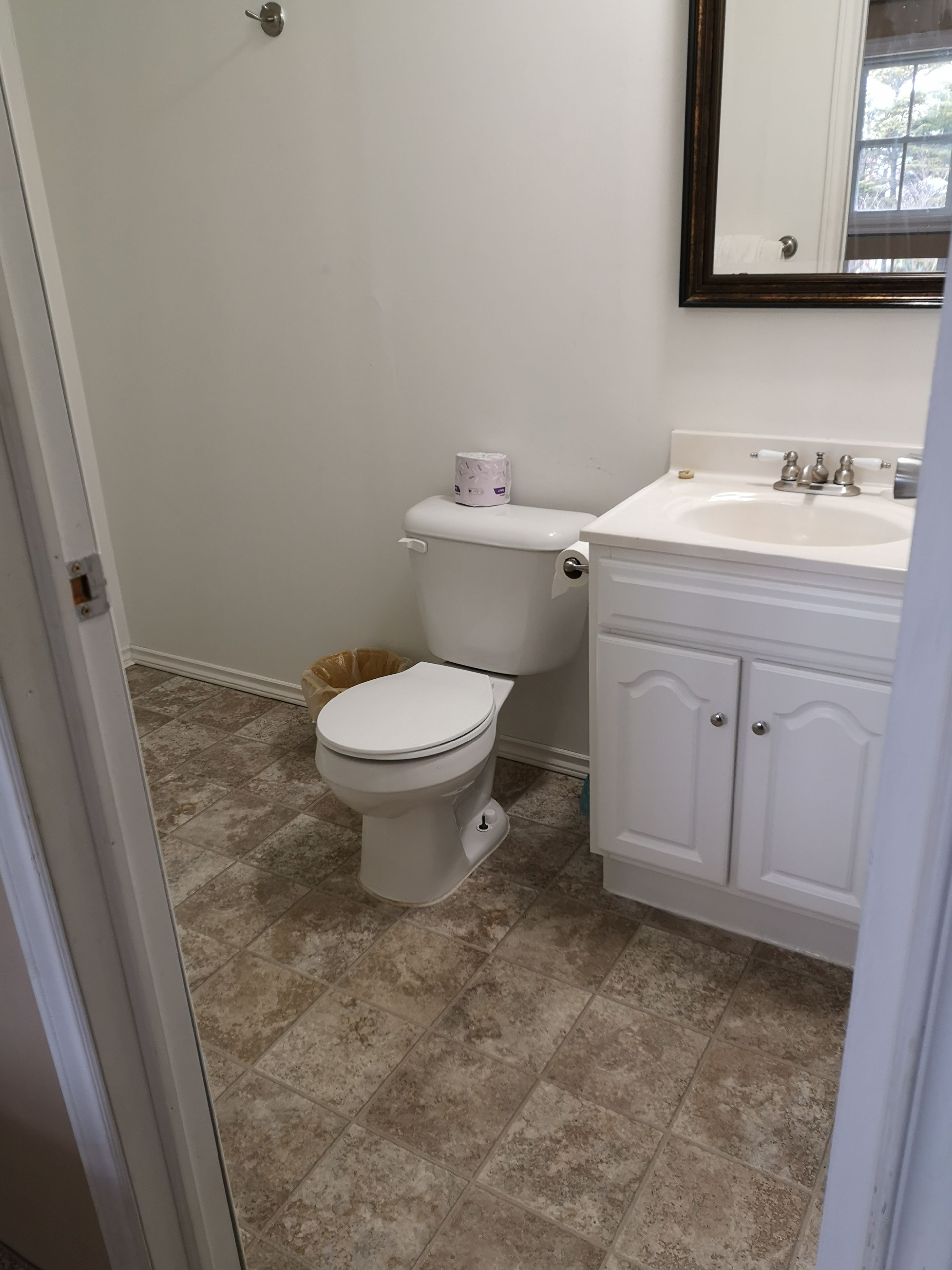 A bathroom with a toilet, sink, and cabinet.