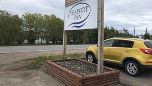 Señal de Seaport Inn, con un comedor y un SUV amarillo estacionado cerca.