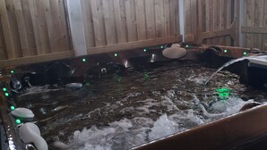 Un jacuzzi con múltiples chorros, rodeado de paneles de madera y una estructura de celosía.